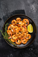 Grilled spicy Shrimps Prawns with garlic and lime in a plate. Black background. Top view