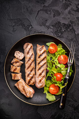 Salad with grilled beef and pork sausages on plate. black background. top view