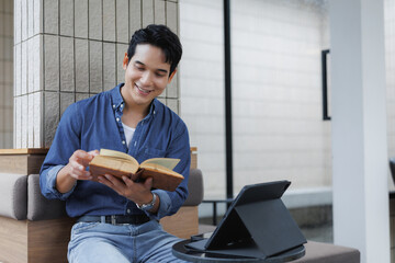 Young man smiling and reading a book in a modern cafe