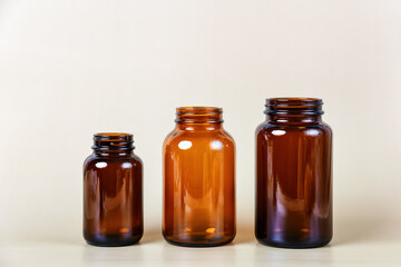 A set of three amber glass bottles stand in a row on a light background, each a different size. Perfect for showcasing pharmaceutical packaging