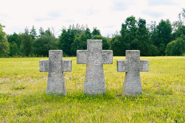 Three German crosses stand in a field at a cemetery.