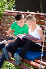 Fototapeta premium Brothers share a storybook moment on a swinging bench, bathed in sunlight. Connection, exploration, and summer vibes. 127 characters
