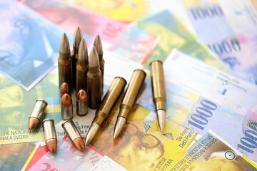 Swiss franc banknotes and bullets. The current francs money bills and ammo lies on table