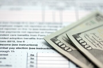 Hundred dollar bills and 1040 individual income tax return form blank close up