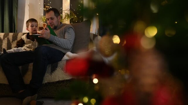 family of three: parents and little son reading fairy tales at home in the evening in a cozy atmosphere of a house decorated for Christmas. New Year's Eve, Christmas celebration with family