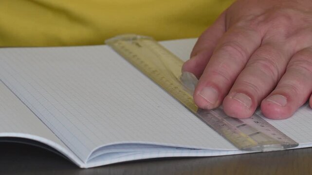 Student practices drawing straight lines with a ruler on graph paper in a classroom setting