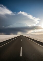 Fototapeta premium Solitary highway vanishing toward horizon beneath dramatic cloudy skies at sunset landscape