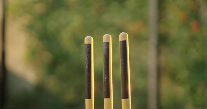 Close up of cricket red ball flying off into air smashing stumps at high speed at ground