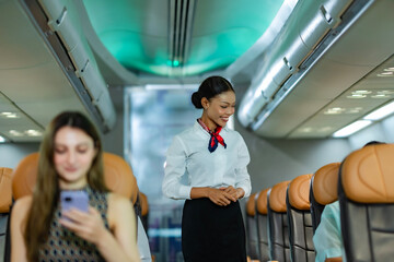 Flight attendant walking down the aisle and speaking kindly to passengers, delivering professional...