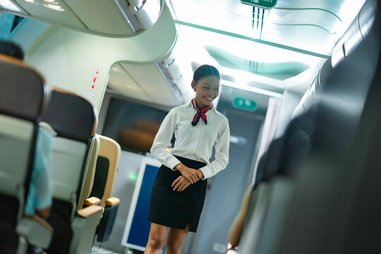 Airline stewardess walking confidently while exchanging friendly words with passengers, ensuring a calm and pleasant atmosphere on board.