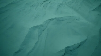 Teal-toned snow-covered mountain peaks, textured and rugged. 