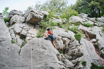 Boy climbing natural rock wall in mountain landscape