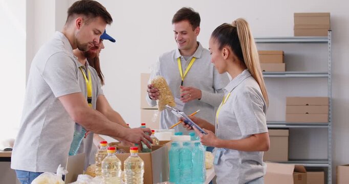 Group of positive volunteers packaging food items into boxes at a humanitarian center. Team collaborative effort reflects commitment to making a difference through donation and charity.