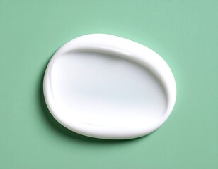 Oval-shaped dollop of white cream on a muted green background