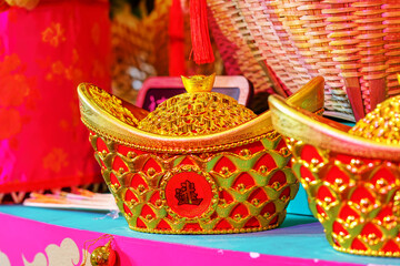 Red and gold Chinese ingots (Yuanbao) with intricate patterns arranged in a festive setting.
