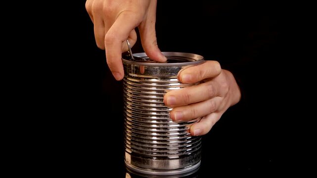 Hand Opening Metal Can of Canned Food on Black Background
