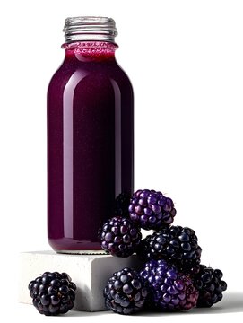 A glass bottle filled with fresh blackberry juice sits near a pile of blackberries against a white background.