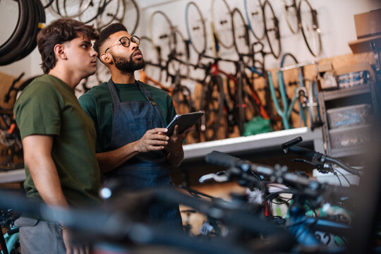 Bicycle mechanics using digital tablet discussing a repair in their workshop