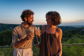 Couple enjoying drinks on balcony at sunset with panoramic view