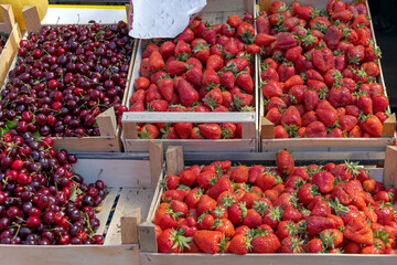 Red Strawberries and Sweet Cherry Fruits in Wooden Crates at Farmers Market
