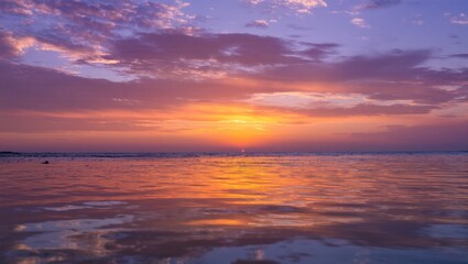 Obraz premium Beautiful, dramatic orange and red sunset over the tranquil sea with clouds and sunlight on the horizon