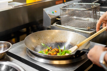 Professional chef stir-frying vegetables and meat in a wok with rising steam in a commercial kitchen, showcasing dynamic cooking at high heat.