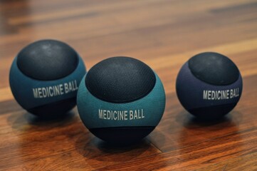 Three Medicine Balls on a Wooden Floor Closeup Focus.