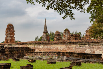 Fototapeta premium Ancient temple ruins and brick wall structures in Ayutthaya Historical Park, Thailand