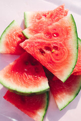 Fresh watermelon slices on pastel pink background, minimal summer fruit concept