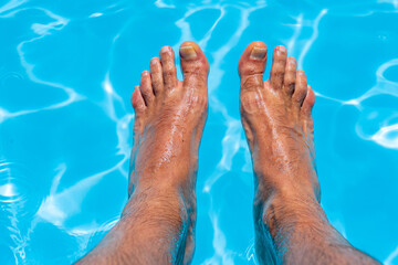 Beautiful feet with 30 centimeters of white Caucasian man inside blue water and pool