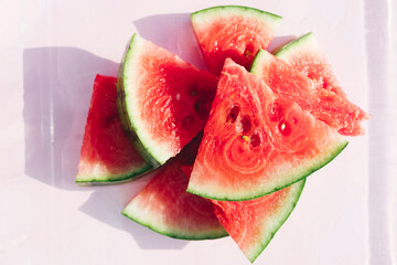 Fresh watermelon slices on pastel pink background, minimal summer fruit concept