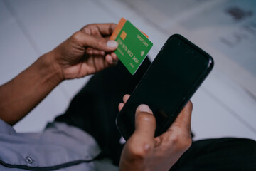 Over shoulder shot of Man using smart phone and credit card for online shopping. Payment concept.
