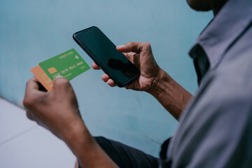 Over shoulder shot of Man using smart phone and credit card for online shopping. Payment concept.