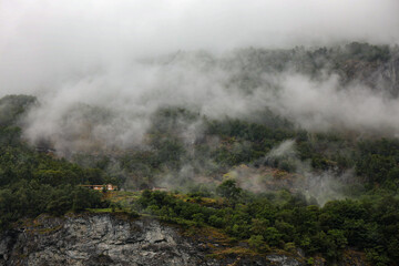 Fog and clouds in the mountains of Norway, Scandinavia. Lonely house in the mountains.