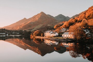 Calm mountain village reflected in a tranquil lake at sunrise