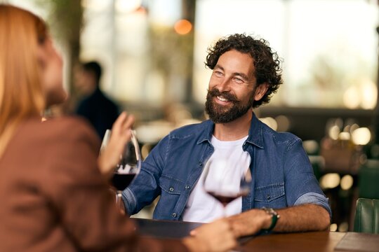 Smiling Couple Enjoying Conversation Over Red Wine at a Cozy Restaurant Table
