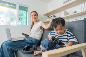 Obraz premium Family Connection. Mother supporting son while he plays video games at home.