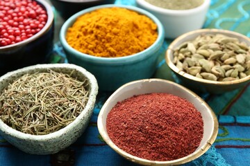 Different aromatic spices on blue tablecloth, closeup