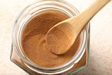 Taking instant coffee powder from jar with spoon at light table, closeup