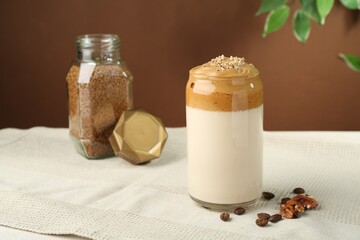 Delicious dalgona coffee in glass, beans, walnuts and granules on table
