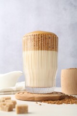 Delicious dalgona coffee in glass, granules and brown sugar on light table, low angle view