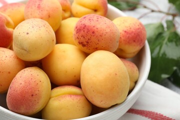 Many fresh apricots in bowl on table, closeup