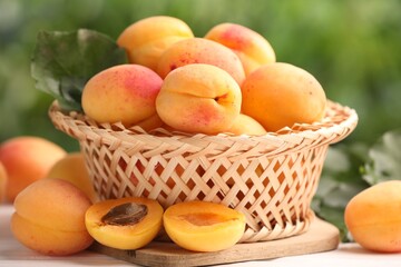 Fresh ripe apricots in wicker basket on table outdoors, closeup