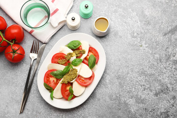 Tasty salad Caprese served with pesto sauce on grey table, flat lay. Space for text