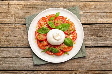 Tasty salad Caprese with mozzarella, tomatoes, basil and pesto sauce on wooden table, top view
