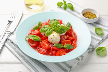Tasty salad Caprese with mozzarella, tomatoes, basil and spices on white wooden table, closeup