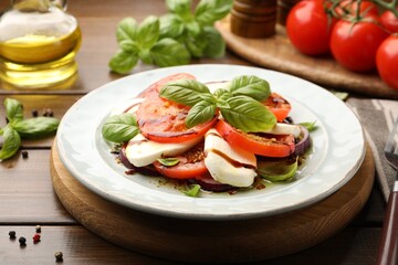 Tasty salad Caprese with mozzarella, tomatoes, basil and spices on wooden table, closeup