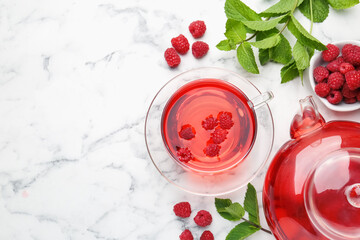 Tasty raspberry tea, berries and leaves on white marble table, flat lay. Space for text