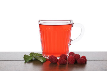 Aromatic raspberry tea in glass cup, berries and green leaves on wooden table against white background