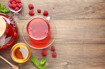 Aromatic raspberry tea, berries, mint and honey on wooden table, flat lay. Space for text